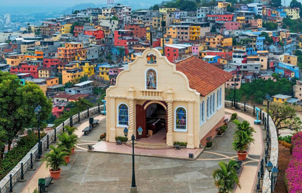 Scenic view of a hillside neighborhood in Ecuador with colorful houses surrounding a small historic church.