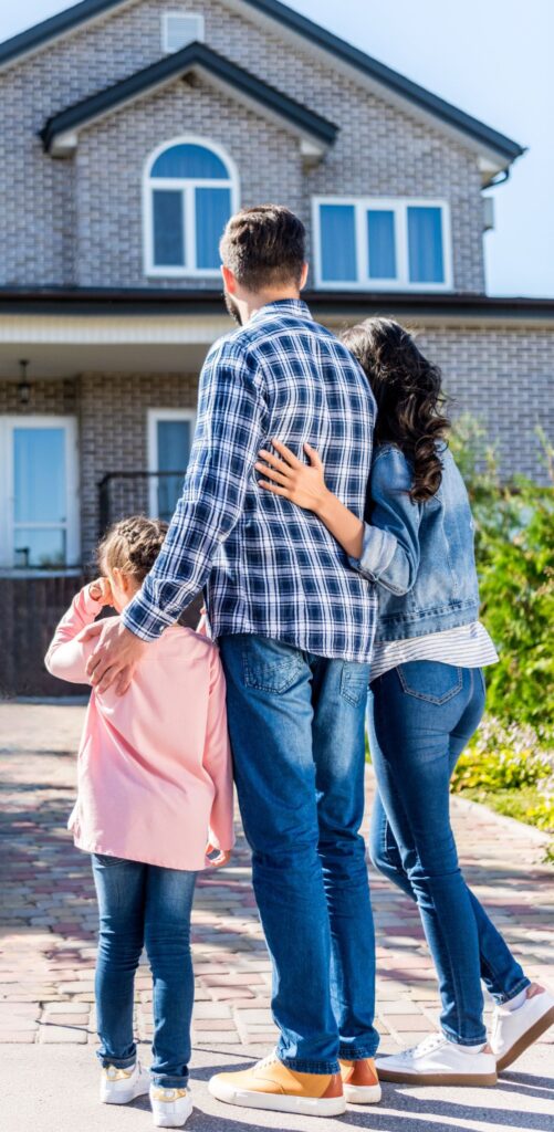 A family standing together and looking at their new house, symbolizing a fresh start and successful relocation.