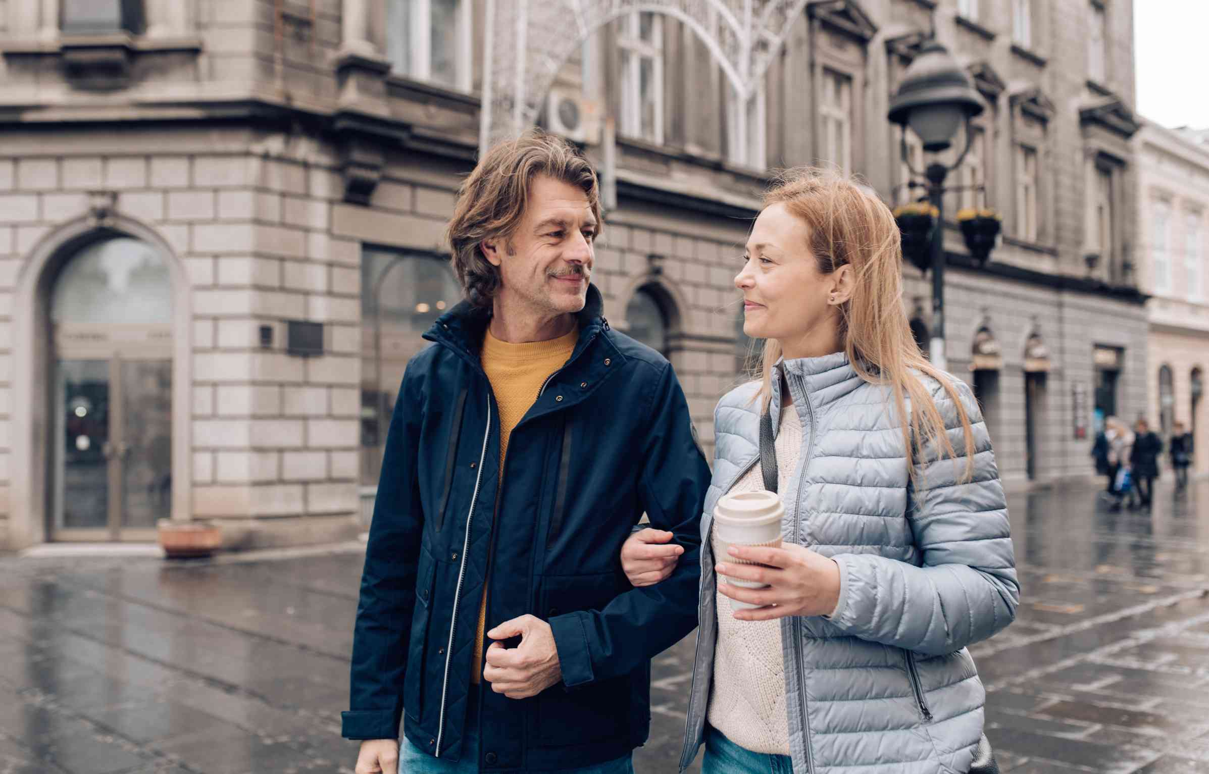 Mature couple walking together on a rainy day in a European city.