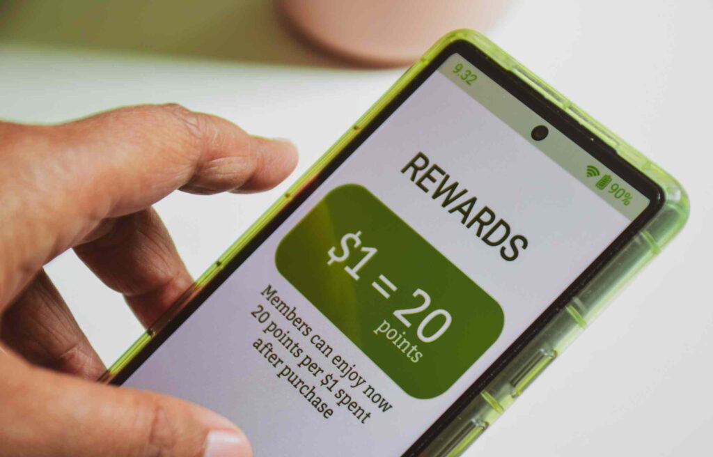 Close-up of a person holding a phone showing “$1 = 20 points,” highlighting how users track reward points through a mobile app.