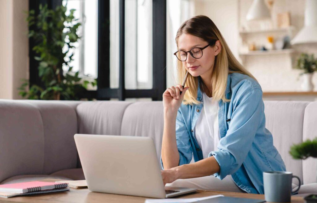 A young woman working remotely from her home office, focused on her laptop while learning ai tools for remote work to improve productivity and collaboration.