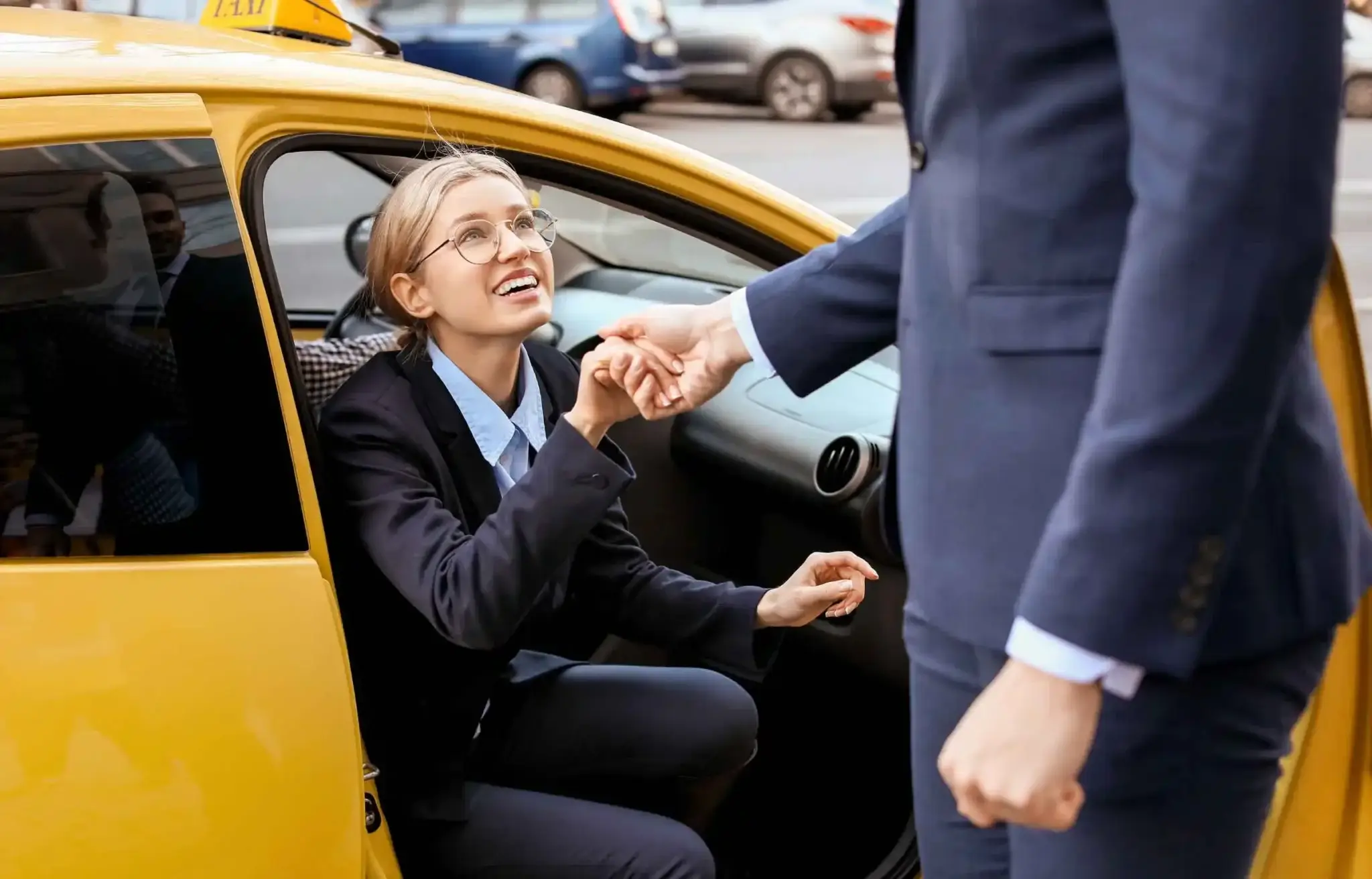 Business traveler being greeted by a professional driver during an airport taxi pickup outside a city terminal.