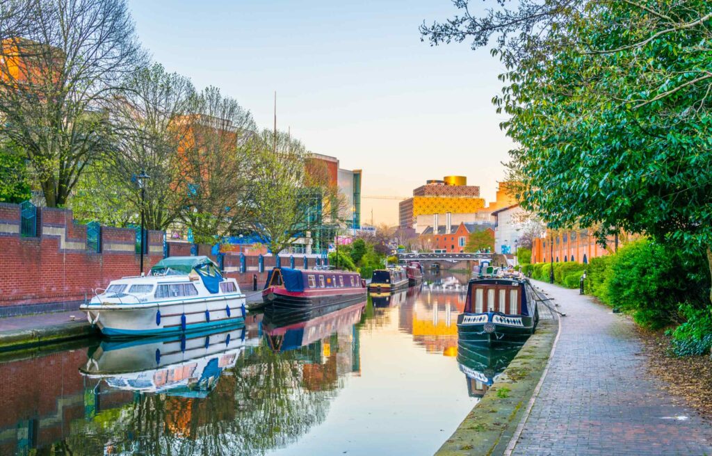 Scenic view of Birmingham’s canal with boats and city buildings in the background.