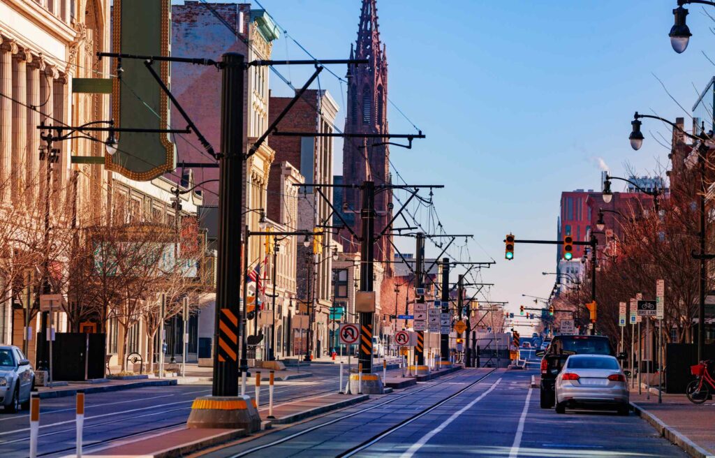 A street scene in downtown Buffalo featuring rail tracks, traffic lights and historic buildings.