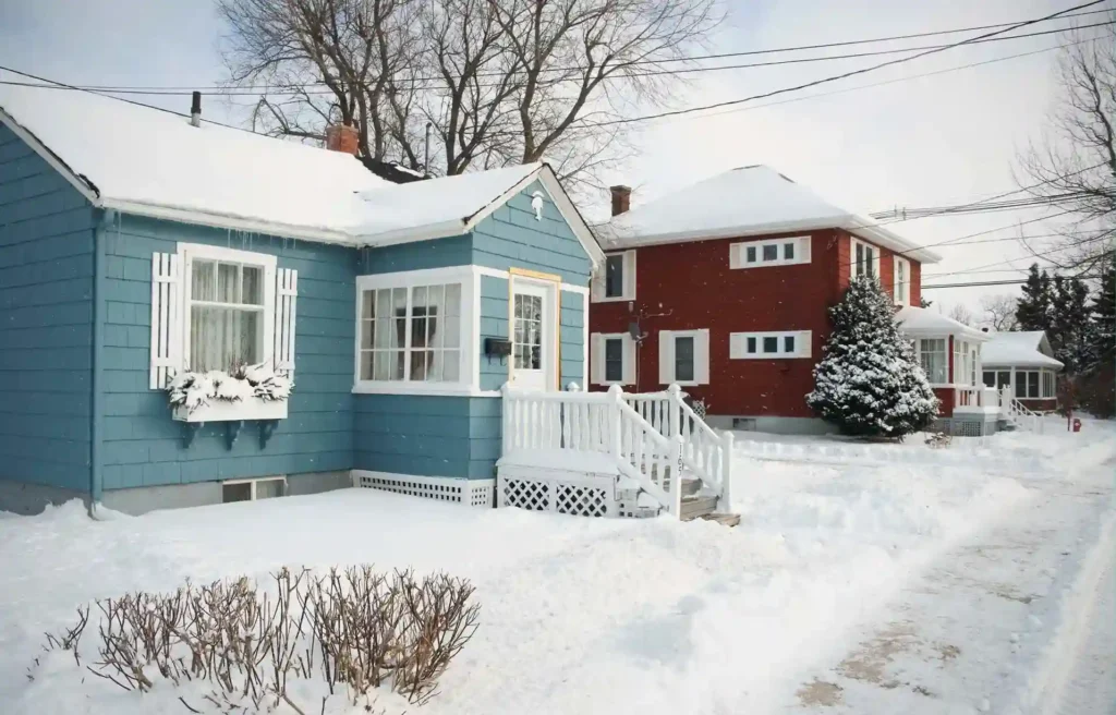Quiet residential street with snow covered houses illustrating winter conditions when selling your home in december.
