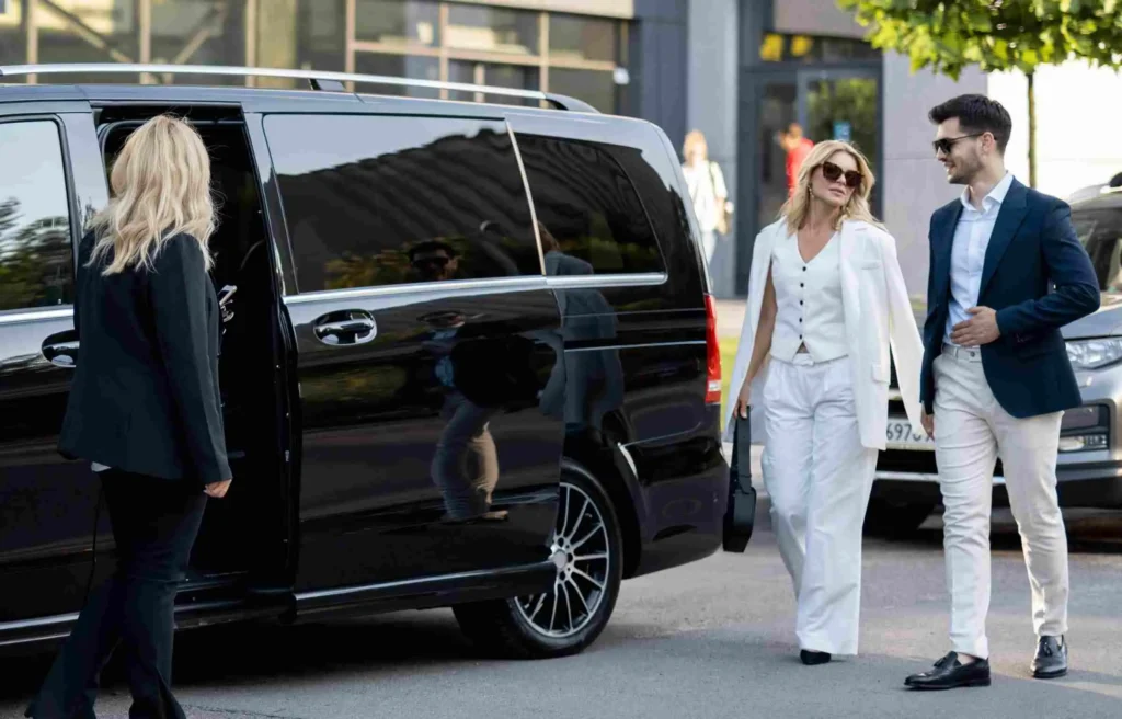 Where are millionaires moving to is reflected in a millionaire couple stepping out of a luxury black van in a refined city setting.