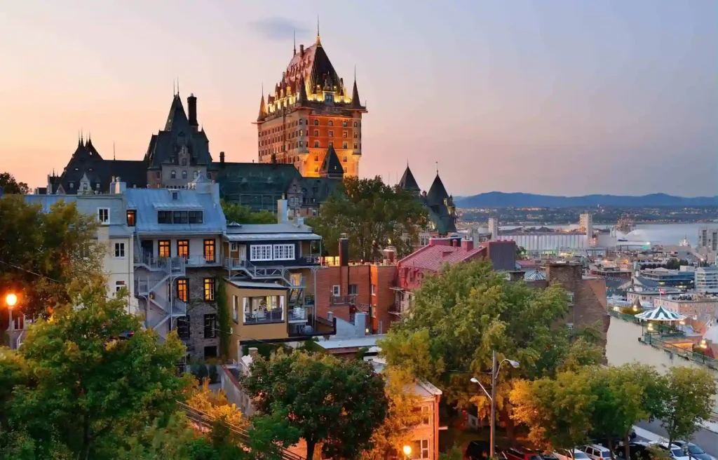 Québec City skyline at dusk with Château Frontenac overlooking historic buildings, river views, and warm evening lights.