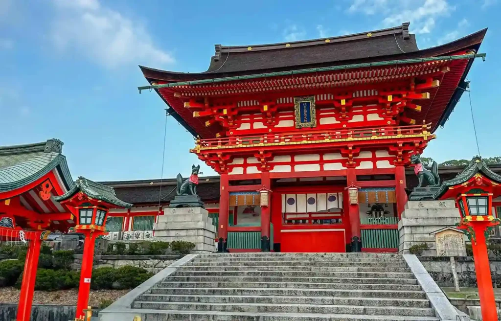 Traditional red Shinto shrine in Tokyo with stone steps, ornate roof, and clear blue sky during the winter season.