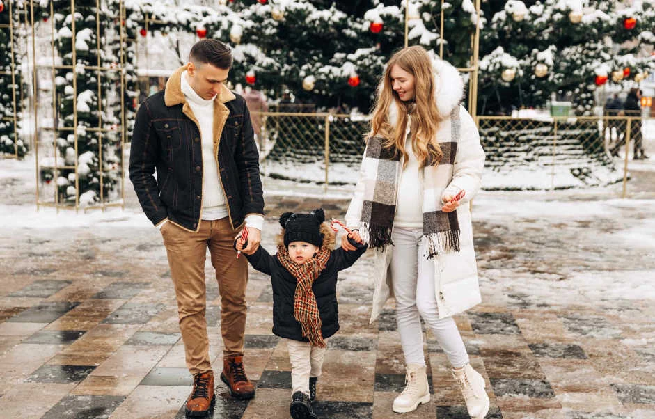 Family walking outdoors in winter while moving during the holidays with a young child.