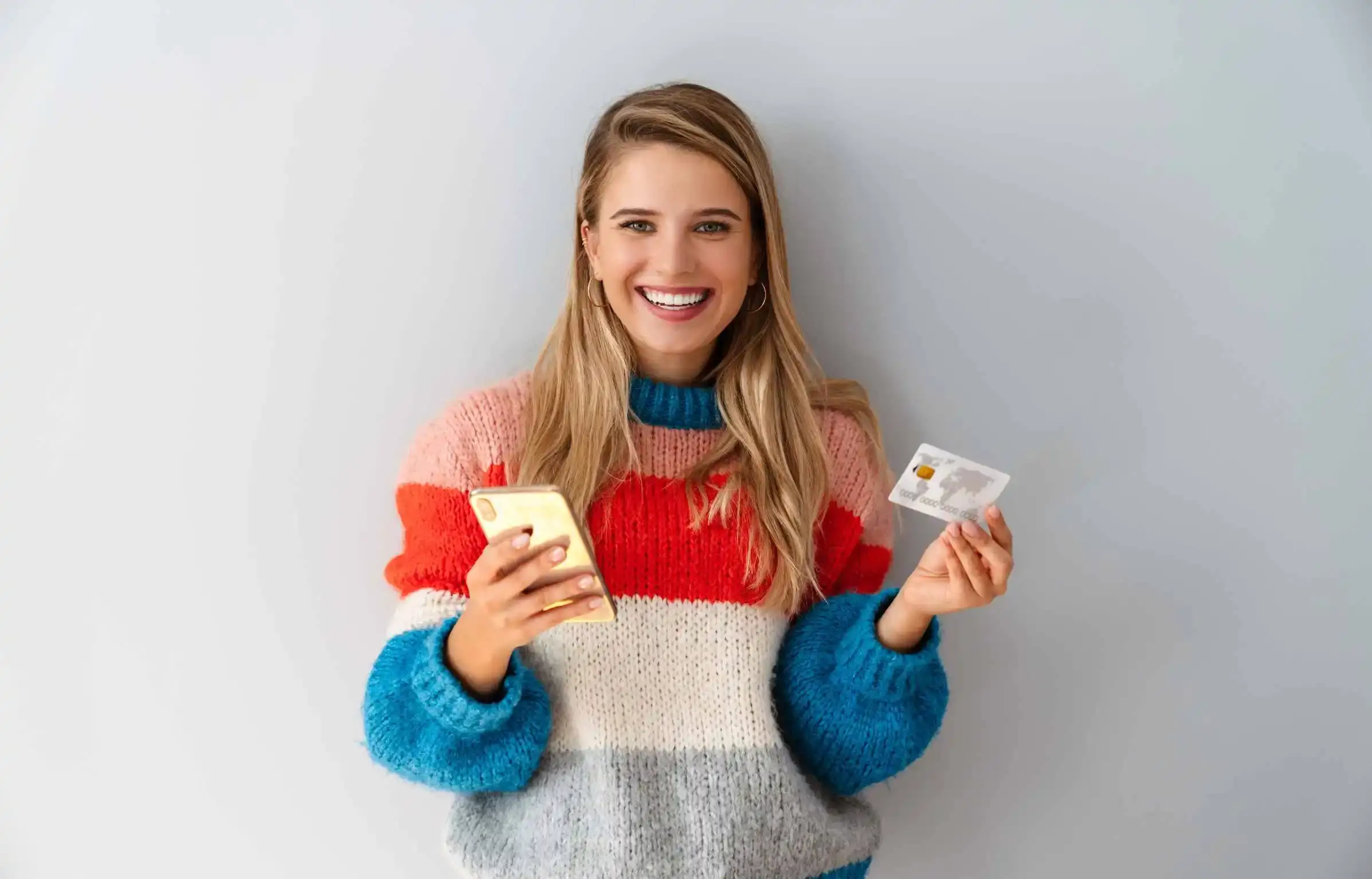 woman comparing credit card details on a smartphone during a new year financial reset.