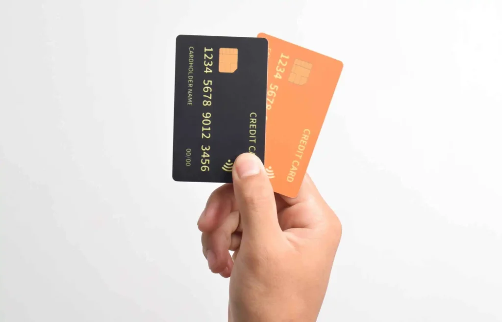 Hand holding two credit cards against a white background, showing business credit card options for new businesses.