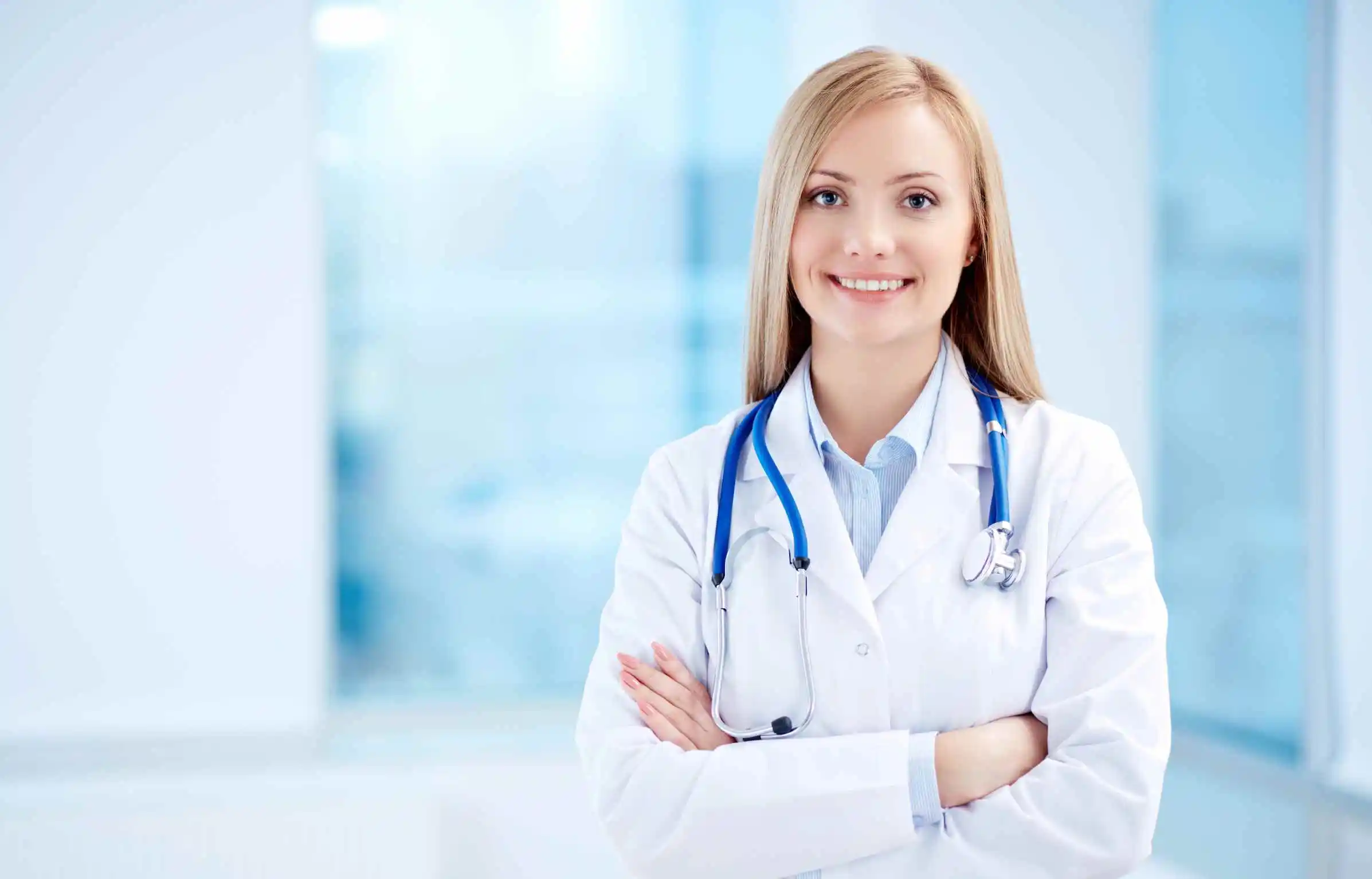 Female physician standing confidently in hospital setting with stethoscope.