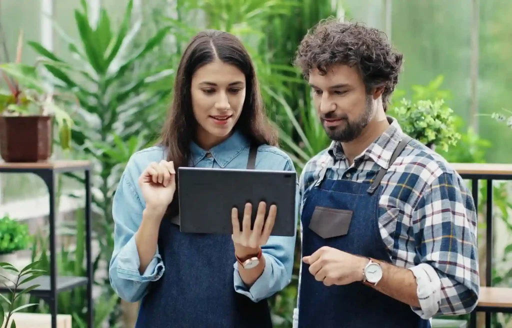 Shop owners reviewing information on a tablet while planning small business retirement plans for employees.