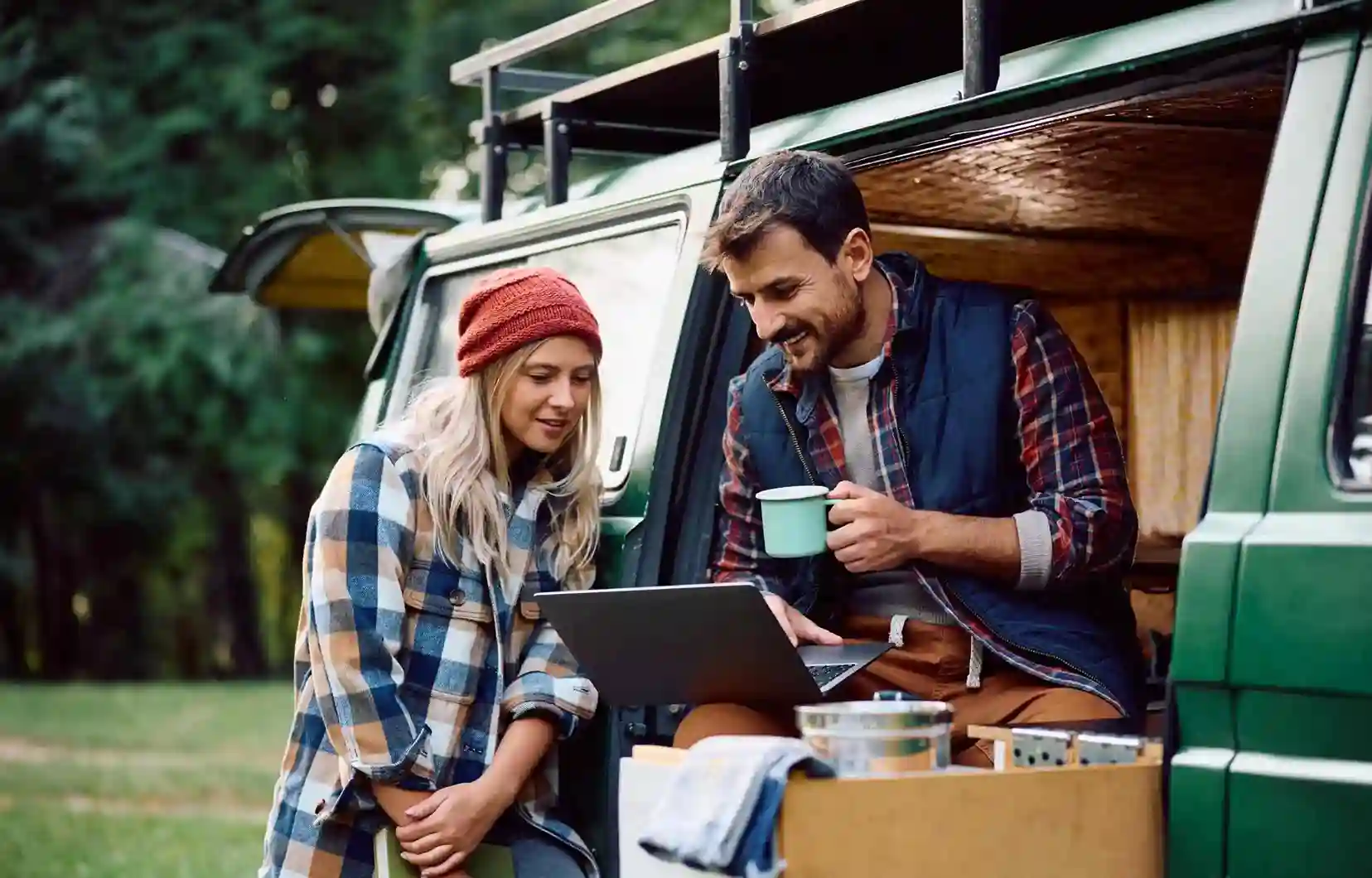 Two digital nomads working remotely on a laptop while traveling in a camper van.