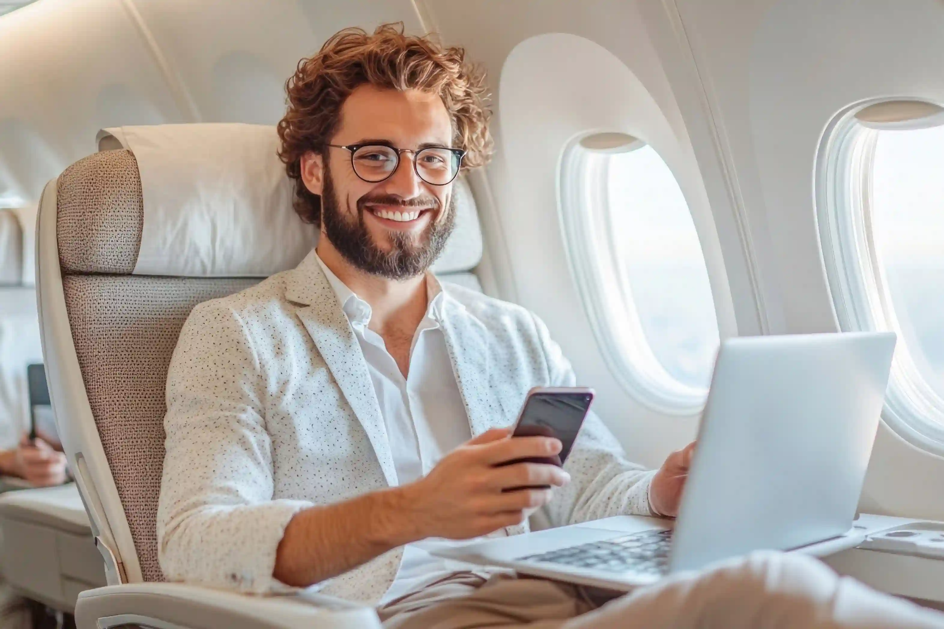 man using laptop and phone with american airlines free wifi during a flight