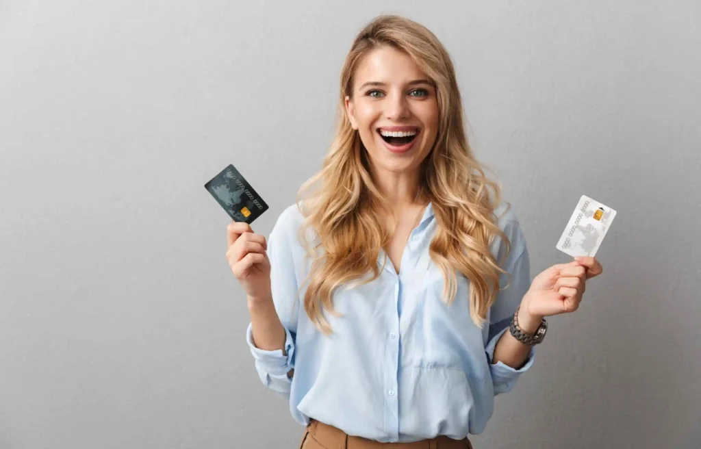 Businesswoman holding two credit cards comparing corporate credit card vs. business credit card.
