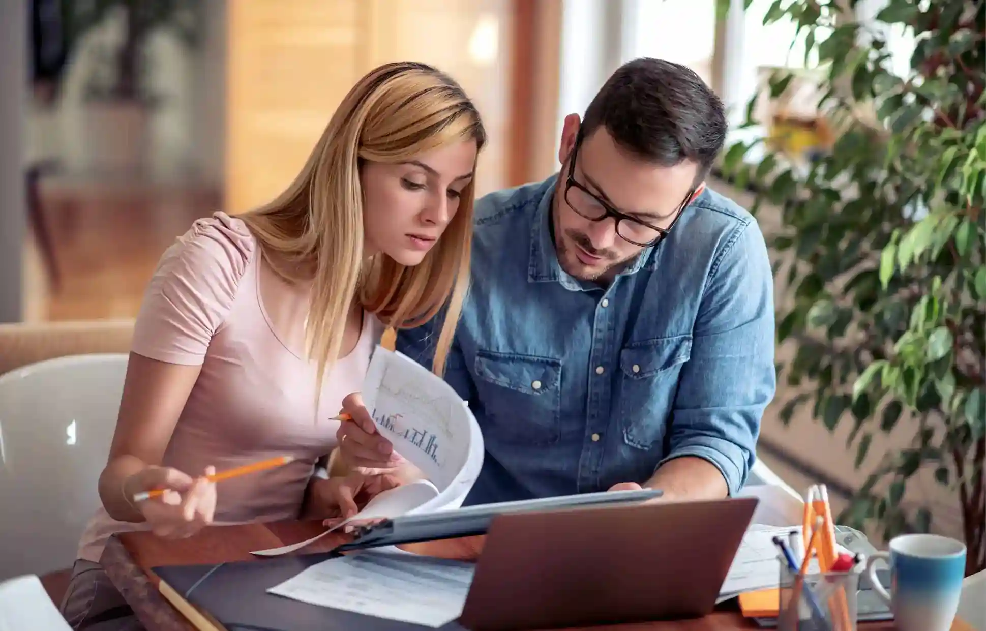 Couple checking bills and budgeting documents while planning finances at home.