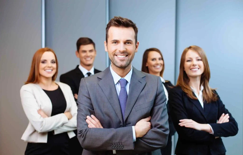 Confident corporate team representing why use a relocation management company in modern office setting.