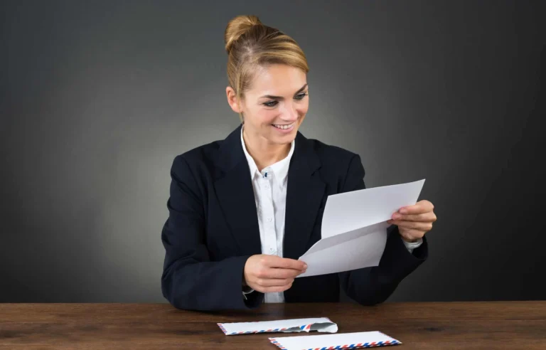 Businesswoman reading a job offer letter at desk before planning a job relocation timeline and move to a new city.