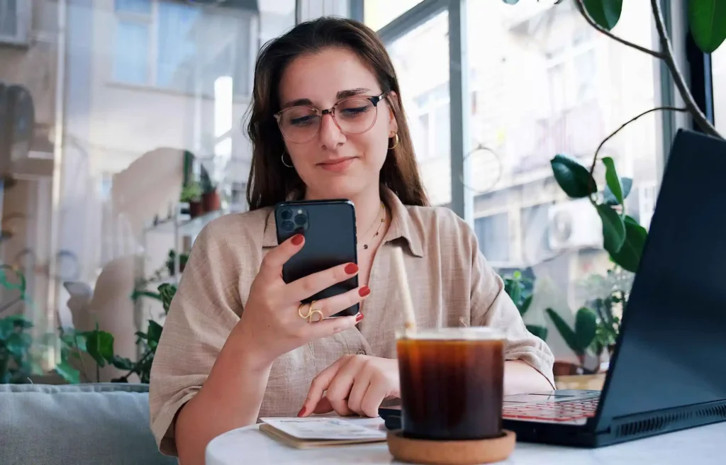 A woman working online from a cafe workspace, illustrating how to become a digital nomad.