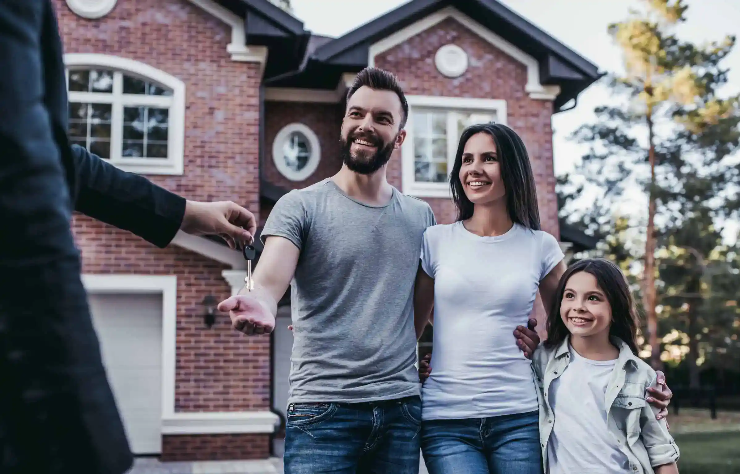 Happy family receiving house keys outside new home representing successful relocating with family transition.