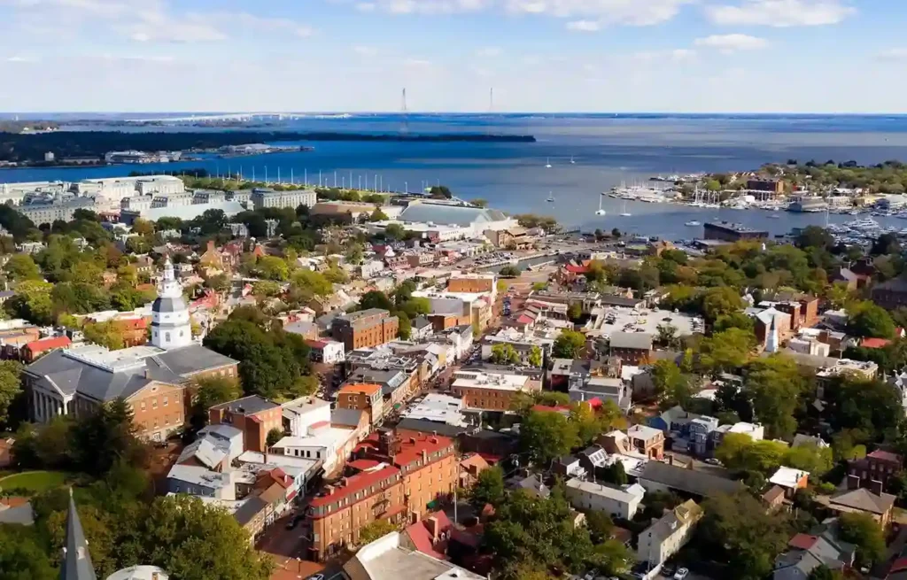 Maryland Annapolis waterfront city view with historic buildings, marina docks, and Chesapeake Bay in the background.
