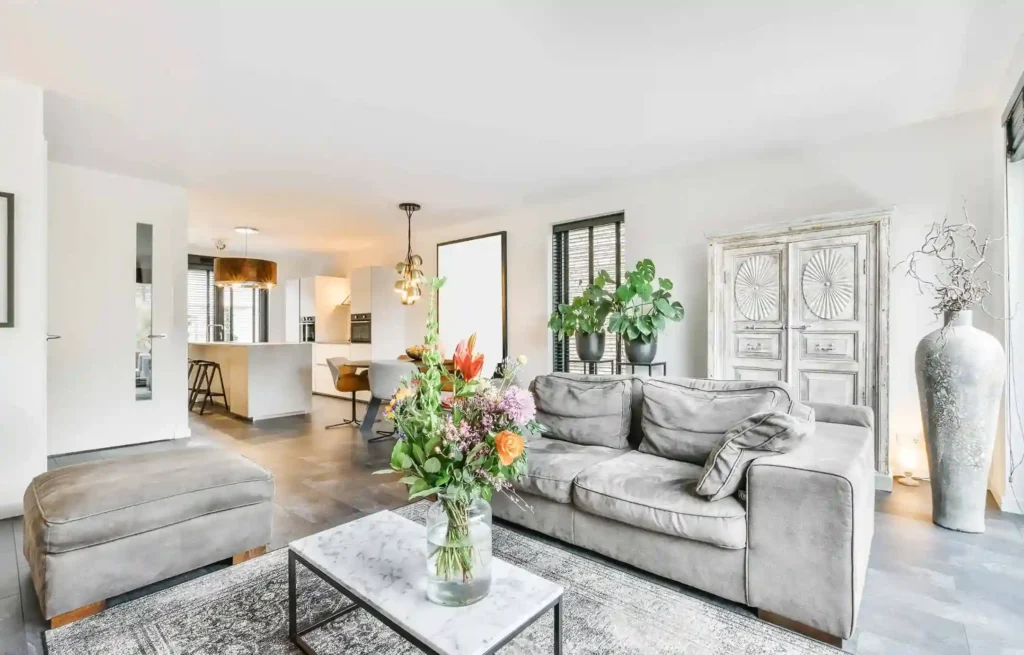 Modern furnished corporate apartment living room with sofa, decor, and open kitchen layout.