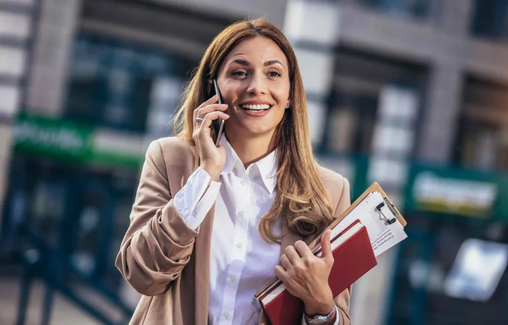 Professional woman on phone reviewing documents after receiving a job offer and starting a job relocation timeline.