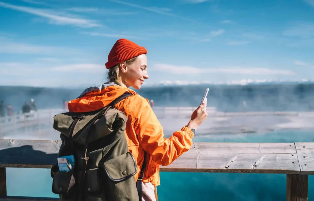 Solo traveler using mobile banking app while enjoying scenic waterfront during international travel.