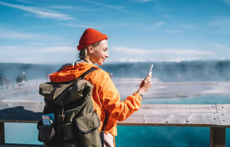 Solo traveler using mobile banking app while enjoying scenic waterfront during international travel.