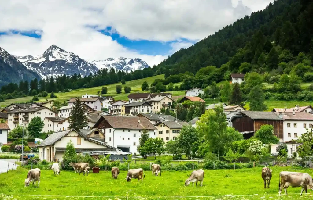 Peaceful Alpine village in one of the safest countries 2026, surrounded by mountains, forests, and green countryside.
