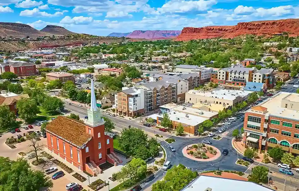 Utah St. George city view surrounded by red rock cliffs and desert landscape under a bright sky.