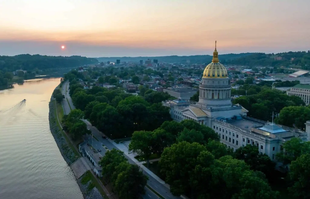 Virginia Charleston capitol building with golden dome beside the Kanawha River at sunset.