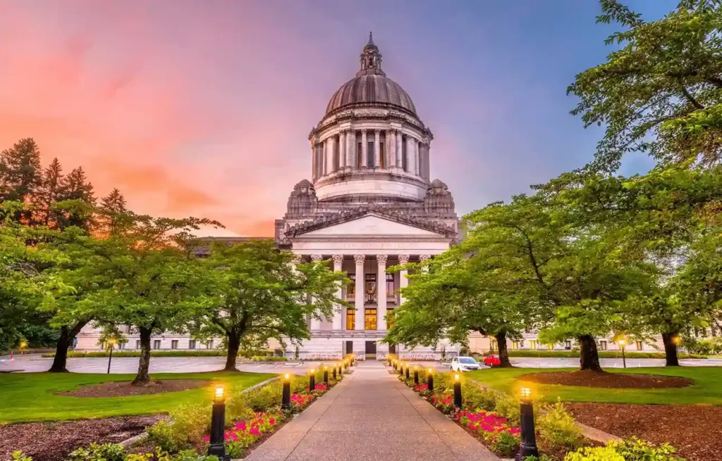 Washington State Olympia capitol building with grand dome surrounded by trees and landscaped grounds.