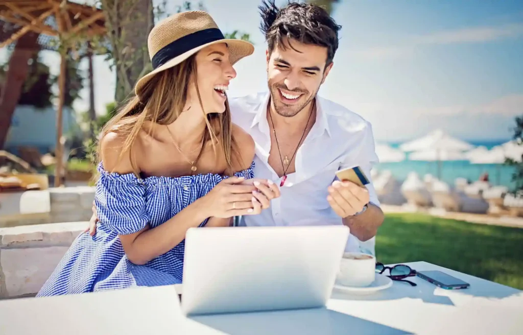 Couple using laptop and credit card outdoors, planning finances during miami relocation.