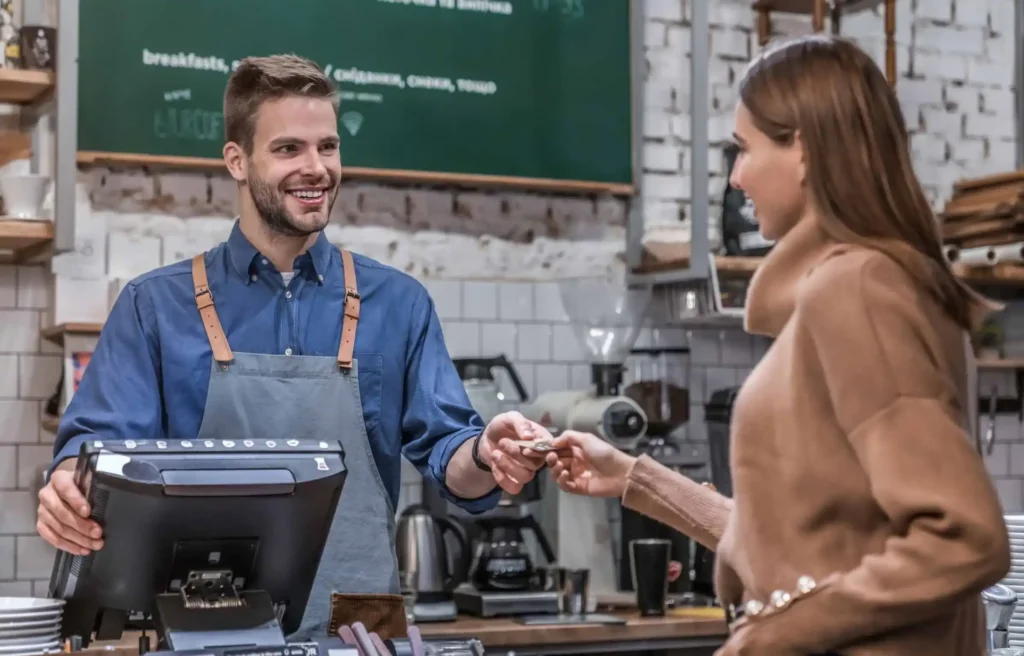 Customer earning credit card points while paying with a credit card at a cafe counter.