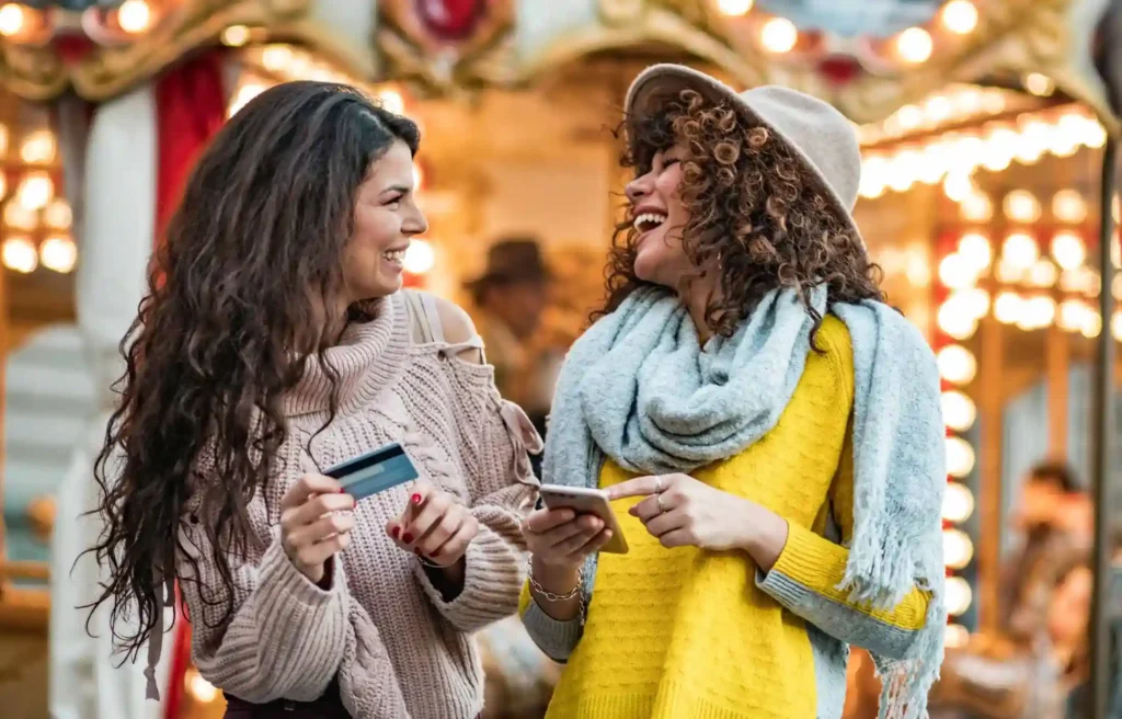 Friends shopping with credit card and phone, using credit cards for your cross-country move during relocation.