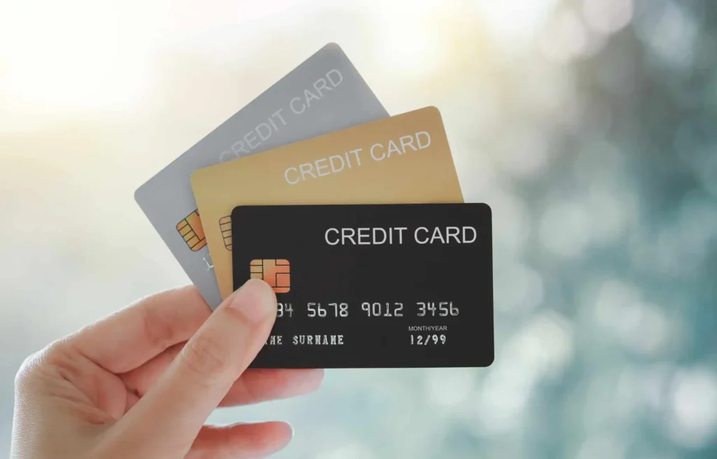 Hand holding three credit cards illustrating multiple credit card bonuses against a soft background.