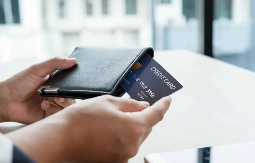 Person taking a credit card out of a wallet for travel expenses using atmos rewards summit visa card.