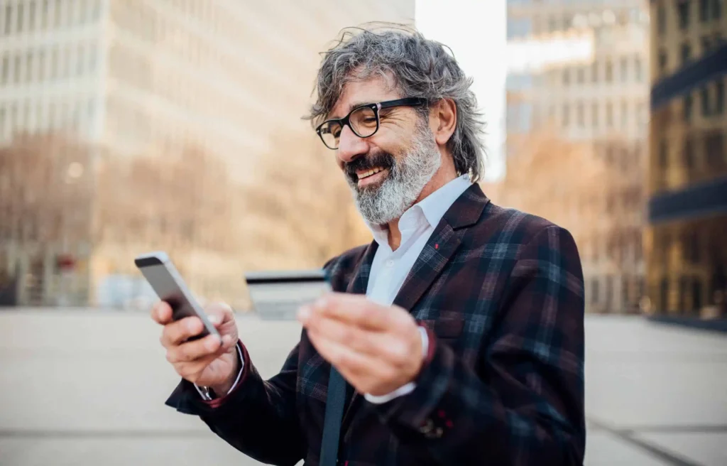 A senior man using a phone for payments while moving, representing credit cards when relocating.