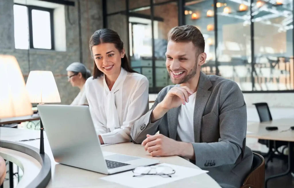 Employees reviewing the best insurance for employees together on a laptop in a modern office.