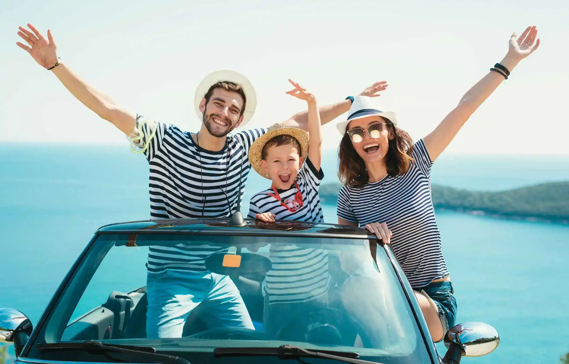 Happy family enjoying a road trip by the sea on a sunny vacation day.
