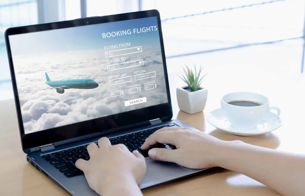 Person booking flights on a laptop while researching the best day to buy airline tickets on southwest, with coffee beside and travel search screen open.