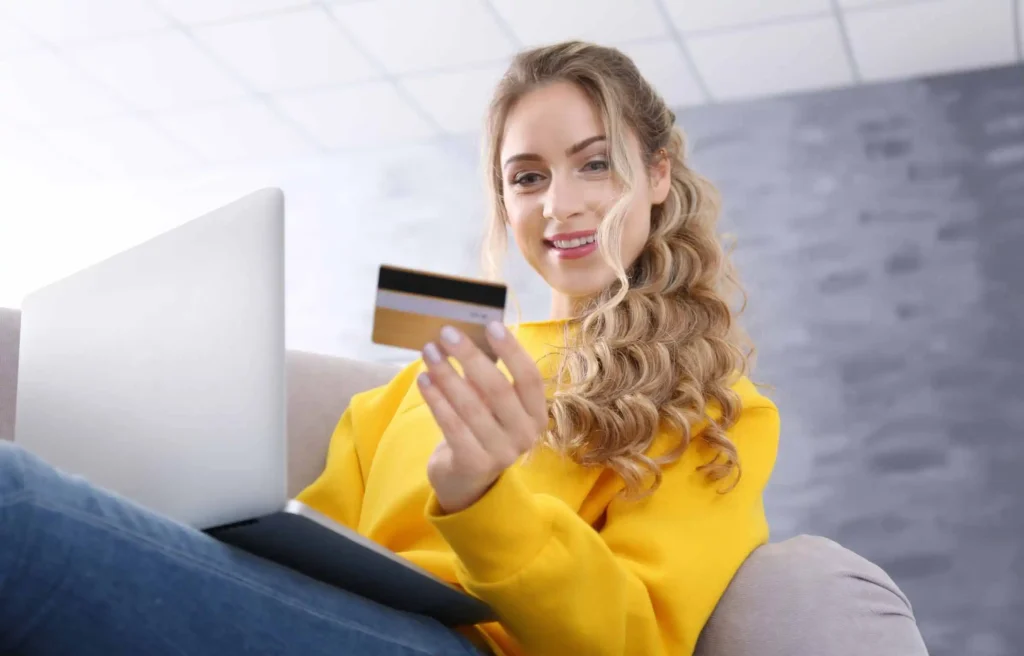 Woman using a credit card to maximize your credit card reward points while shopping online from home.