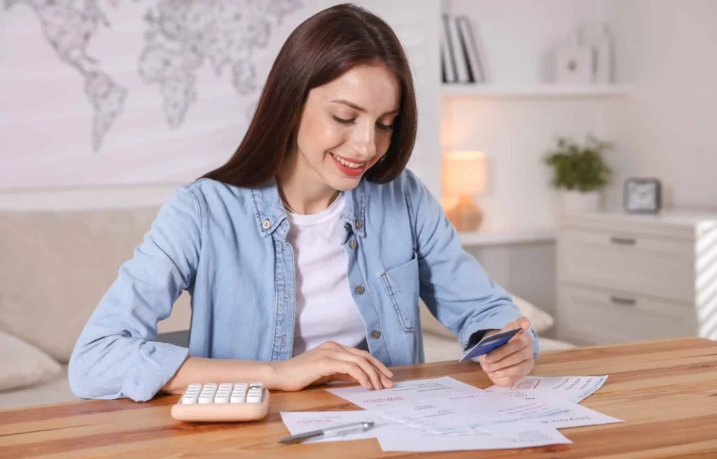 A woman reviewing bills with a credit card and a calculator. Can you pay your property taxes with a credit card?