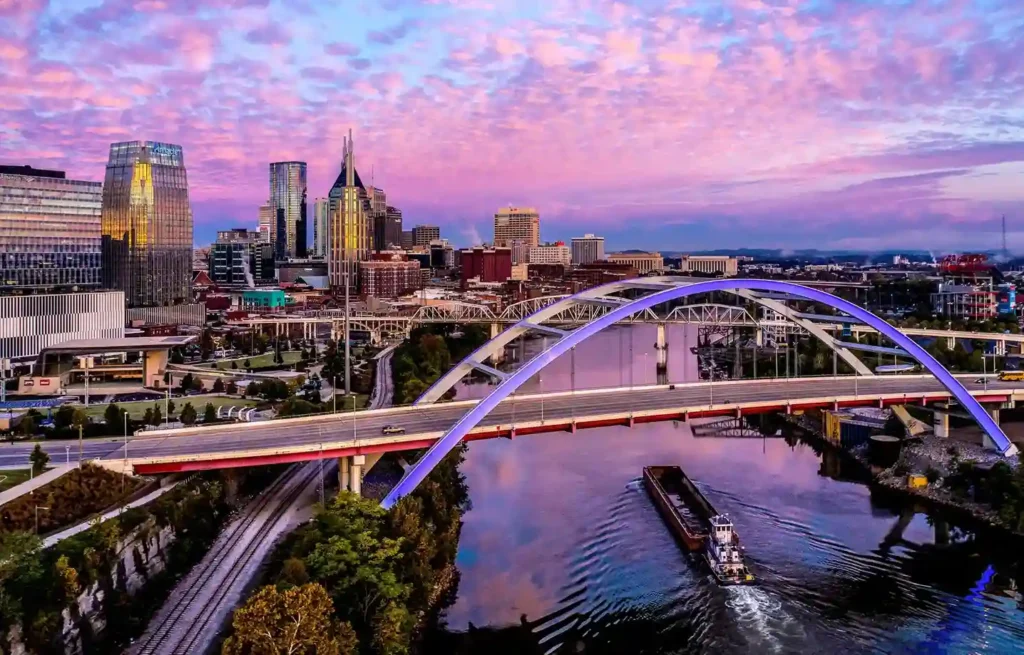 Asheville, North Carolina city skyline, river bridge, and pink sunset sky; best places for Americans to retire.