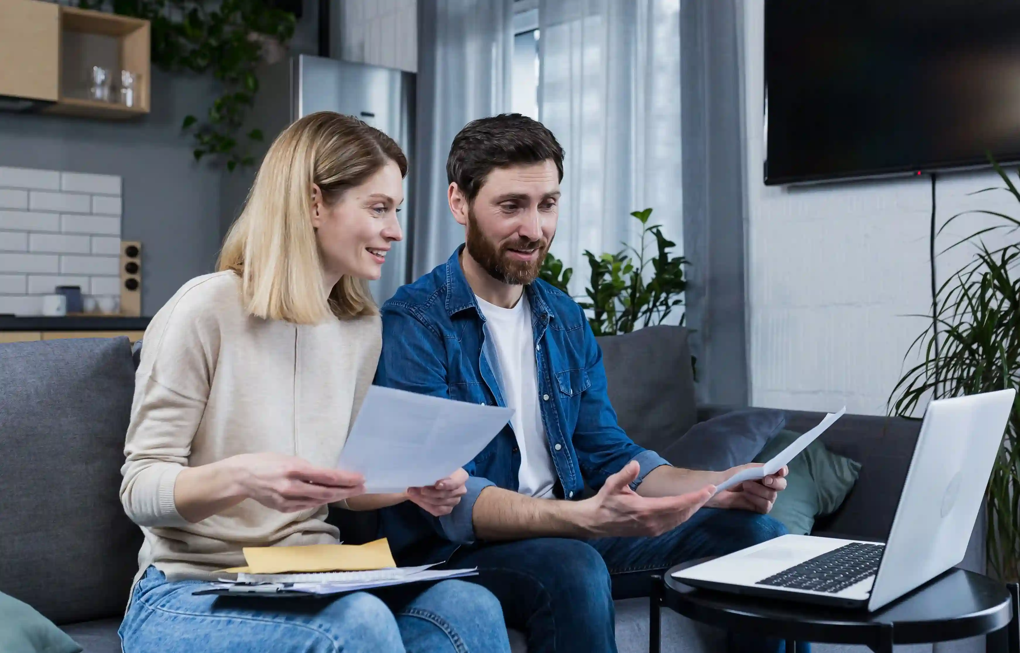 Couple reviewing moving expenses and relocation paperwork on a laptop at home.