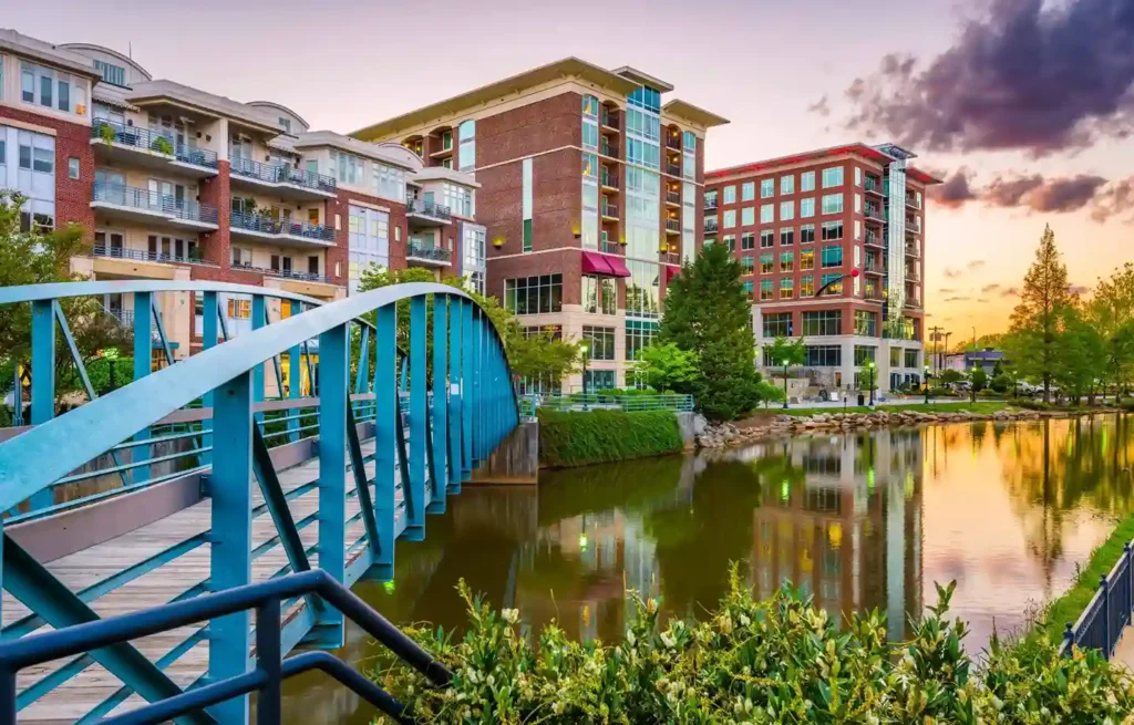 Greenville, South Carolina pedestrian bridge and riverfront apartments at sunset.