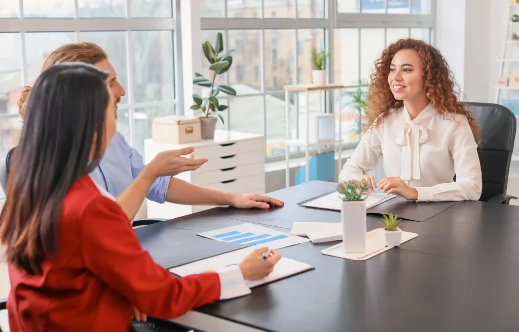 HR representative discussing relocation offer red flags with two employees during an office meeting.