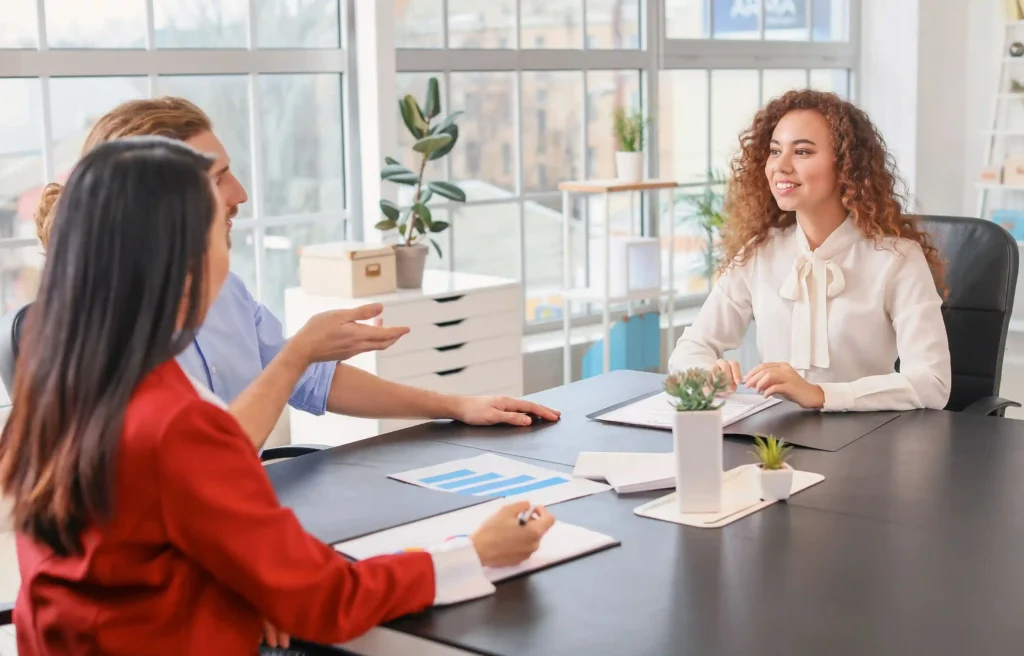 HR representative discussing relocation offer red flags with two employees during an office meeting.